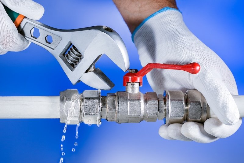 Hands plumber at work in a bathroom, plumbing repair service. Leak of water. Repair plumbing.