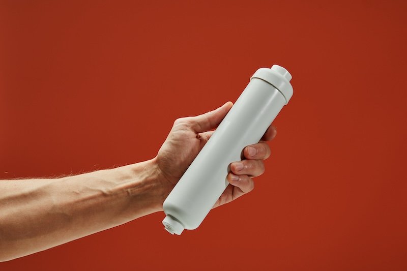 Plumber carefully inspecting water filter cartridge, highlighting professional maintenance and water quality improvement techniques