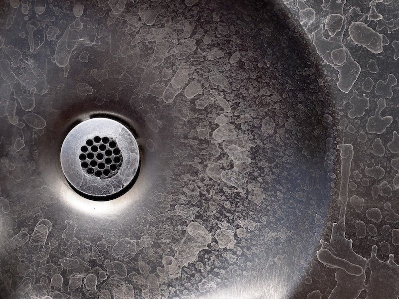 Old metal drain with water stains and marks on steel sink