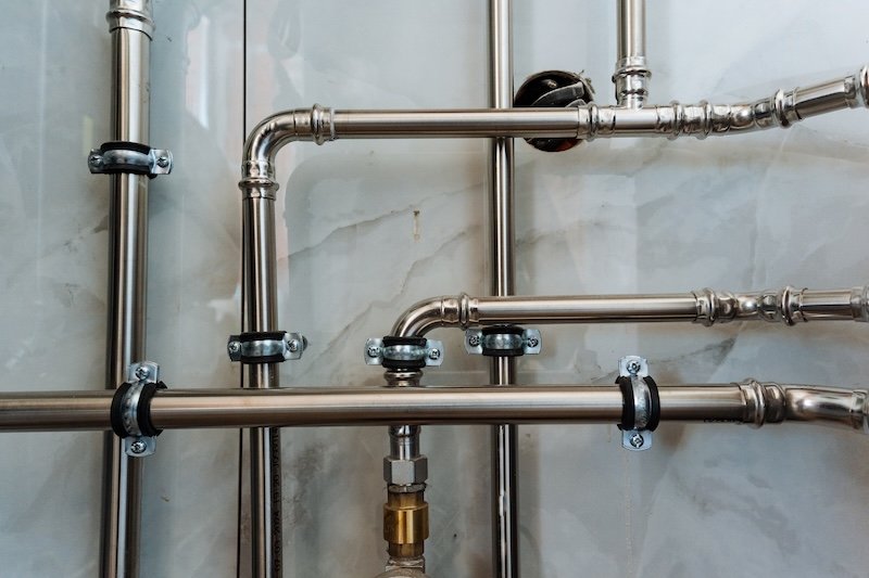 Displayed prominently on the wall is a stunning collection of stainless steel pipes that elegantly hang, showcasing their sleek, modern design and adding a chic industrial aesthetic to the space