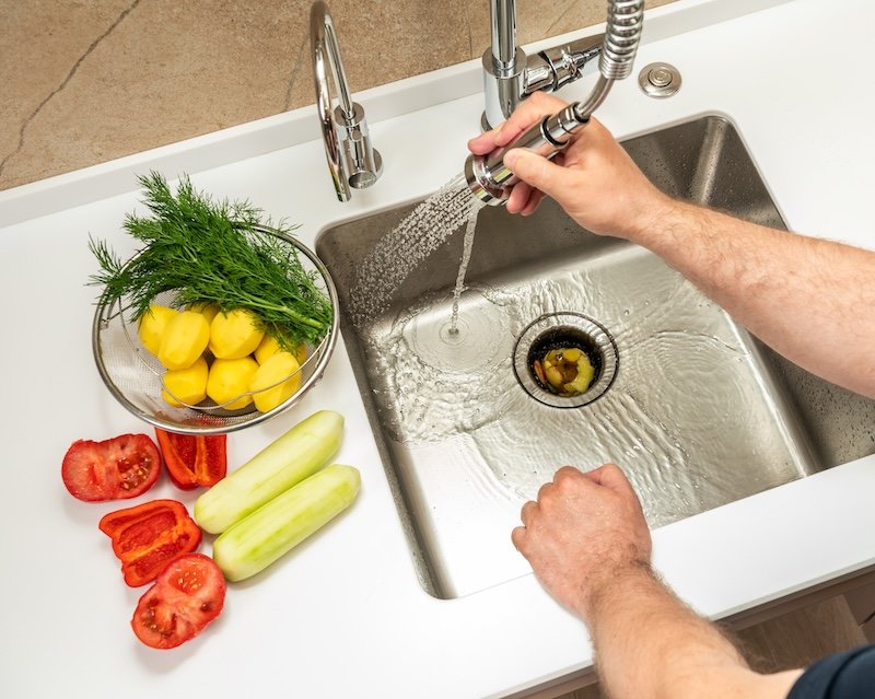 A man washes food waste into a dispenser.