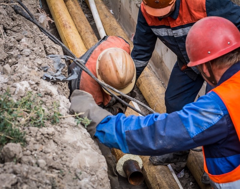 A group of male workers push the heating pipe