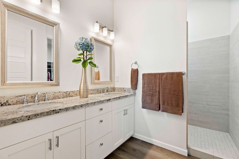 The bathroom features two sinks, a stylish mirror, and a spacious walkin shower for your convenience and comfort