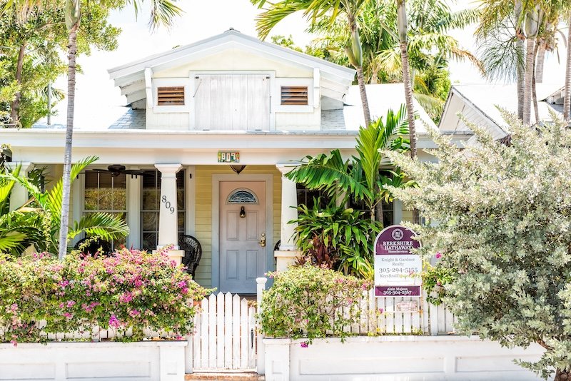 Key West, USA - May 1, 2018: White and yellow architecture of house in Florida city island on travel, sunny day, sign for Berkshire Hathaway property real estate sale