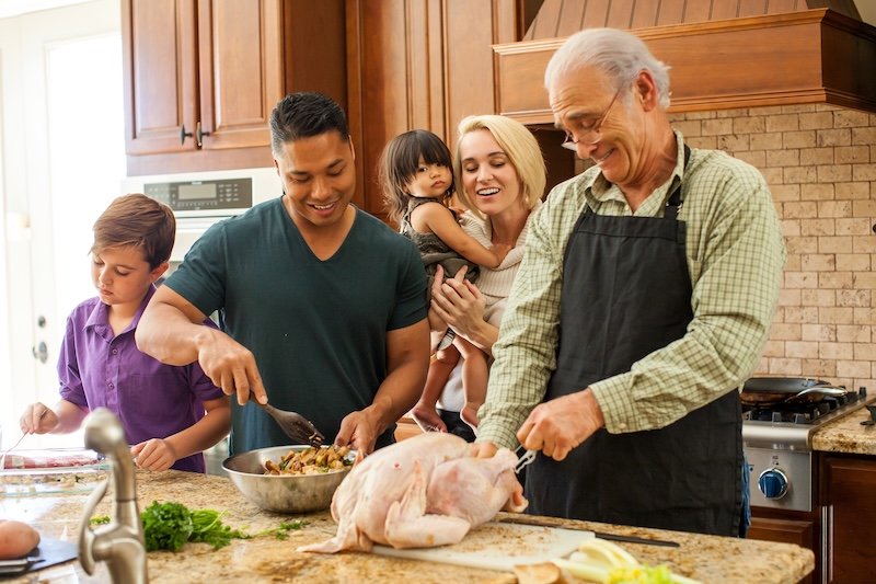 Mixed race family having fun in the kitchen preparing turkey dinner