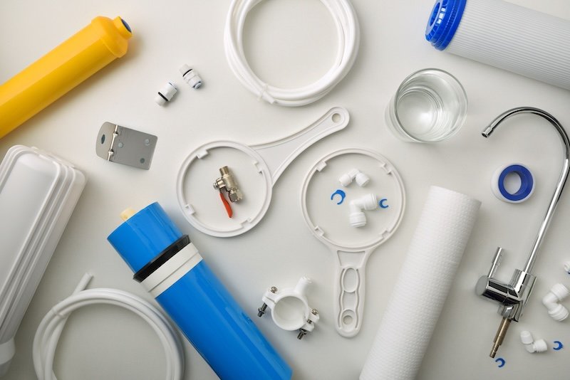 Supply of tools and parts for the maintenance and repair of sanitary water treatment equipment on a white table. Top view. Horizontal composition.