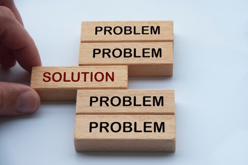 Hand putting wooden block with word solution in the middle of wooden blocks with words problem. Solution concept.